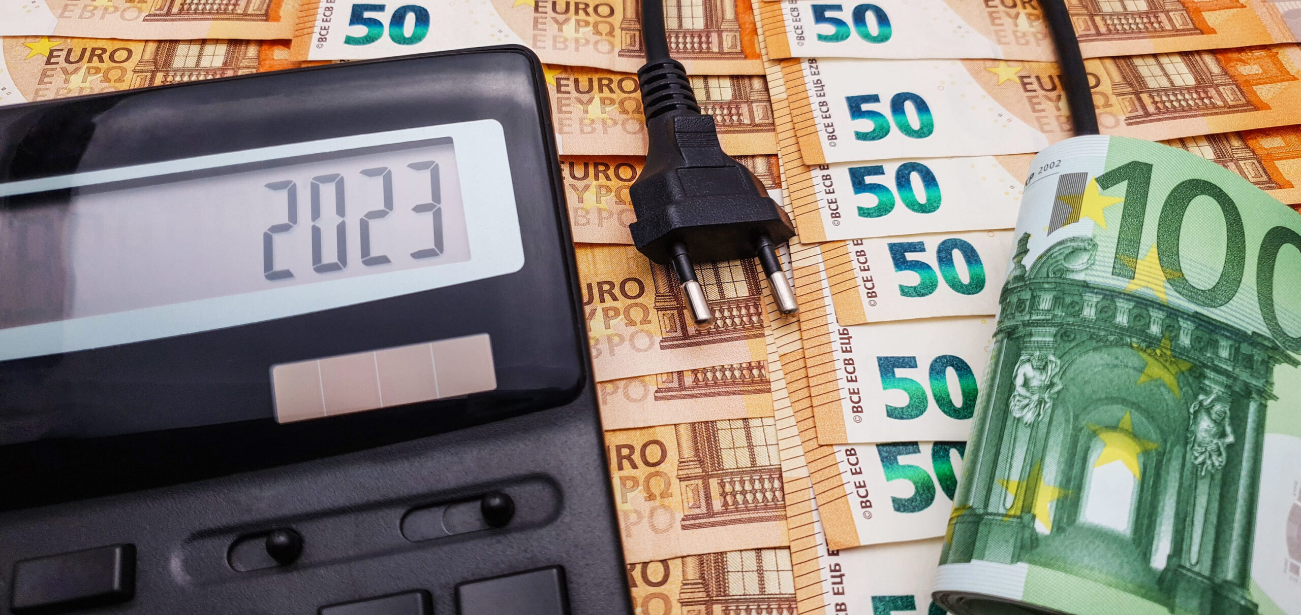 Calcolatrice, spina elettrica e banconote per rappresentare l’aumento delle bollette dell’energia